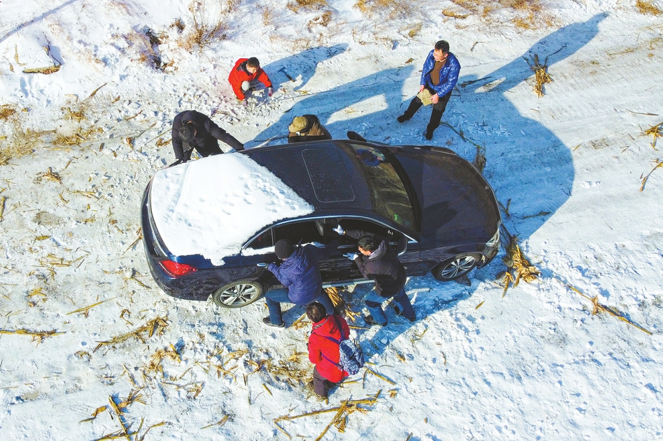 进山被困冰雪路 众游客推车助脱困